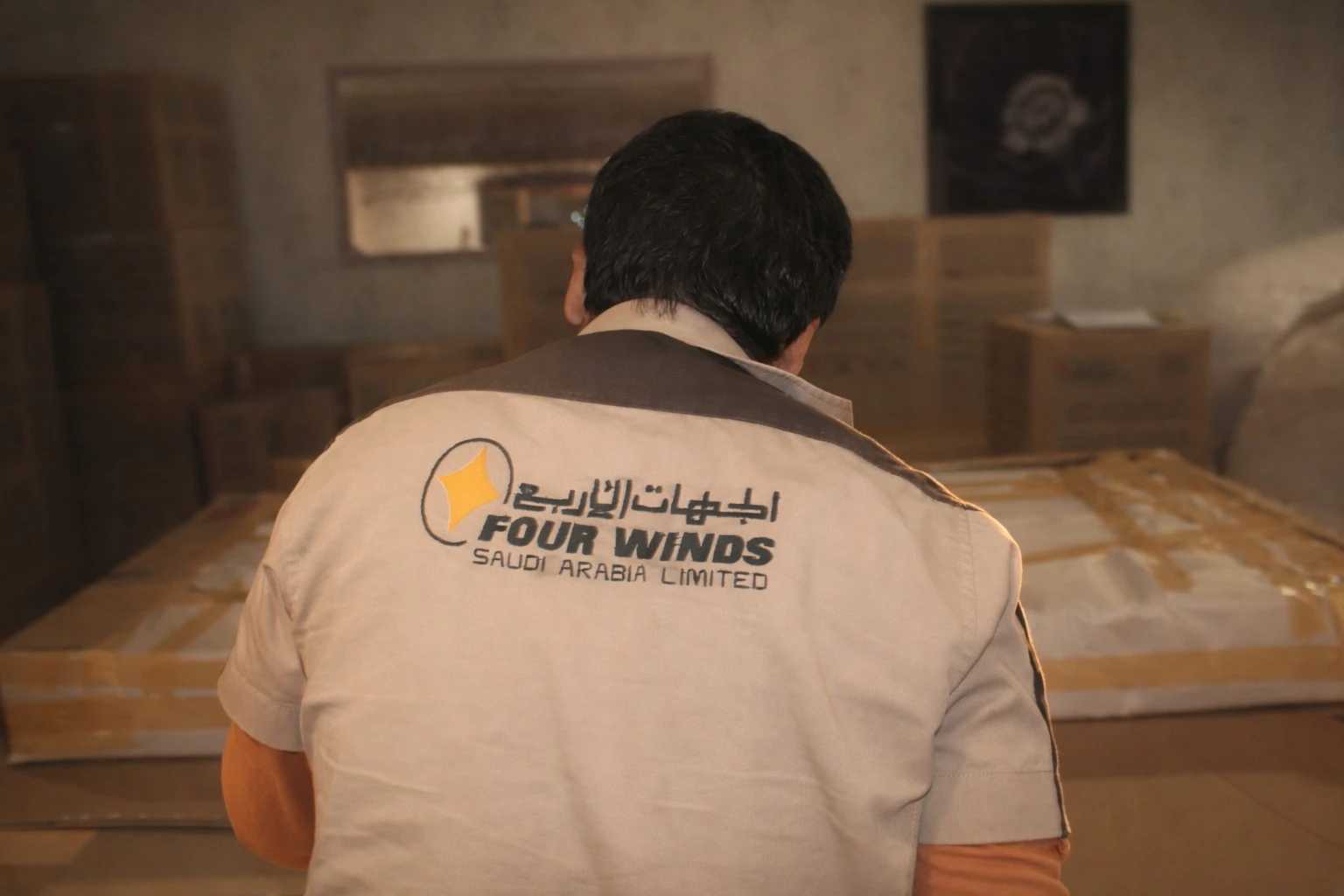 متخصص في التعبئة يرتدي زي شركة الجهات الأربع ويجهز قطعة مغلفة للنقل